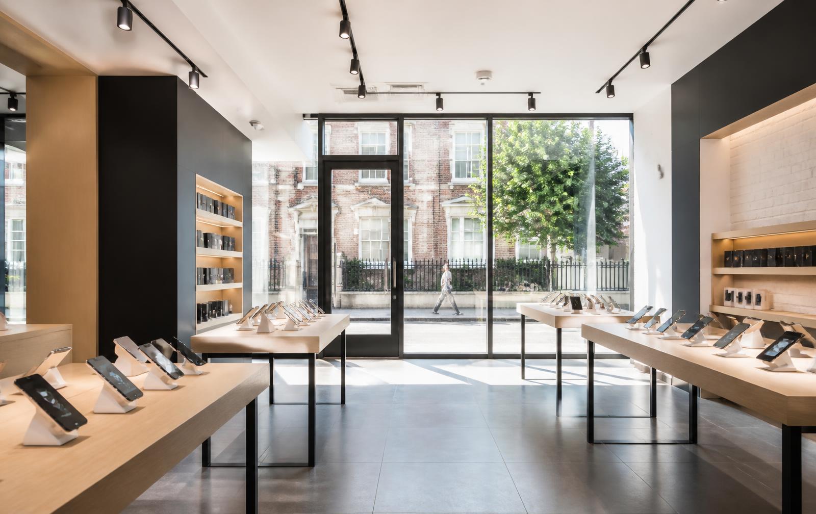 Bright modern mobile phone shop interior with handsets on display tables